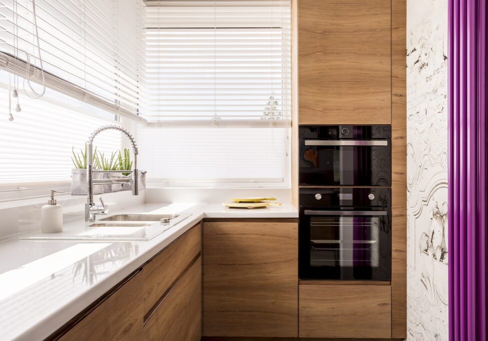 Modern kitchen with wood accents an iron sink and two chopping boards next to a microwave and an oven